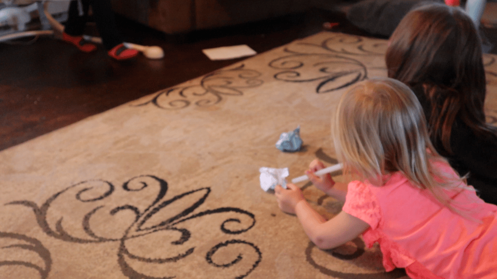 two girls playing on floor having paper race