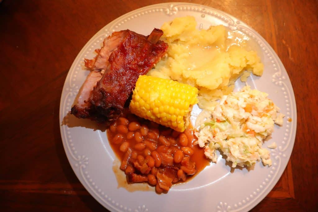 the best bbq ribs in an oven, corn, baked beans, mashed potatoes, coleslaw