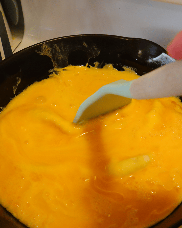 scrambled eggs cooking in cast iron skillet
