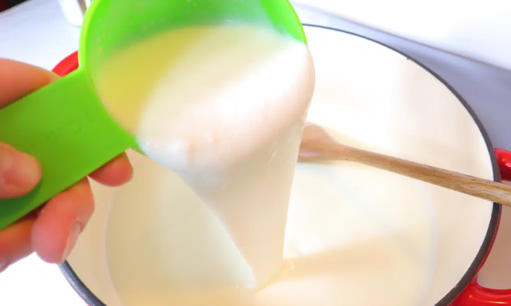 pouring cultured buttermilk into milk for soft cheese recipe